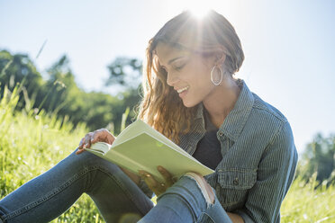 A young woman sitting in the sun reading a book - MINF04172