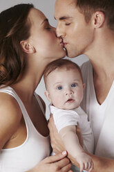 Mother and father kissing, with baby daughter - ISF19649