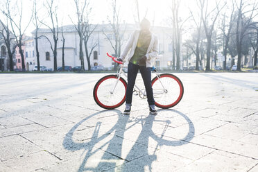 Junge hält Fahrrad auf städtischem Platz - GIOF04070