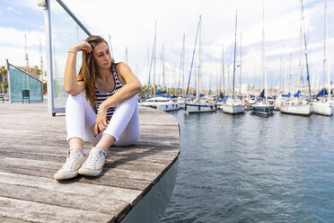 Young woman sitting on promenade at a marina - WPEF00759