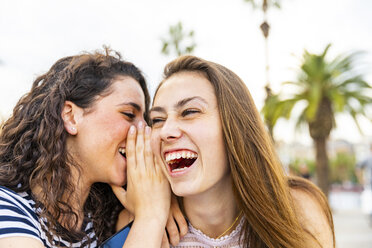 Two happy female friends whispering and laughing - WPEF00769