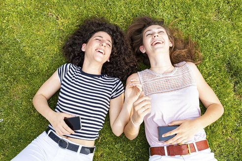 Zwei glückliche Freundinnen liegen im Gras und haben Spaß - WPEF00779