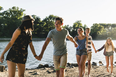 Group of happy friends walking hand in hand at the riverside - UUF14805