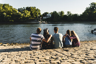 Group of friends sitting at the water looking out - UUF14807