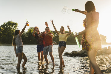 Gruppe von glücklichen Freunden in einem Fluss bei Sonnenuntergang - UUF14818