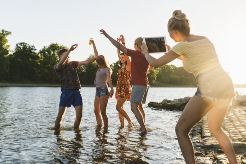 Gruppe von glücklichen Freunden mit Tablet in einem Fluss bei Sonnenuntergang - UUF14821