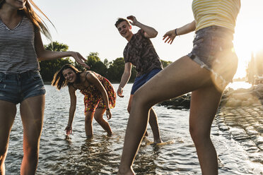 Gruppe glücklicher Freunde, die sich bei Sonnenuntergang in einem Fluss vergnügen - UUF14824