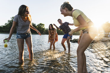 Gruppe glücklicher Freunde, die sich bei Sonnenuntergang in einem Fluss vergnügen - UUF14825