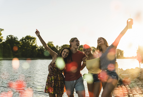 Group of happy friends having fun in a river at sunset stock photo