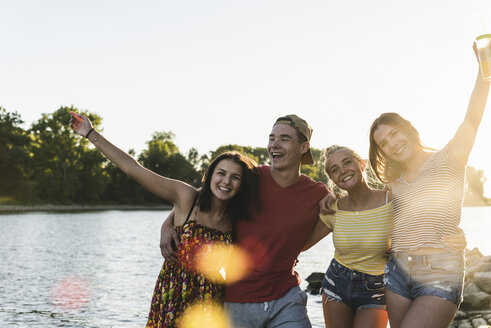 Group of happy friends having fun in a river at sunset - UUF14829