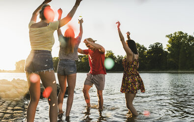 Gruppe glücklicher Freunde, die sich bei Sonnenuntergang in einem Fluss vergnügen - UUF14830