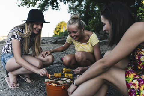 Drei junge Frauen sitzen zusammen und grillen, lizenzfreies Stockfoto