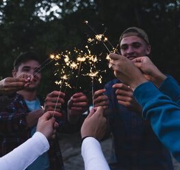 Group of friends holding sparklers in the evening - UUF14850