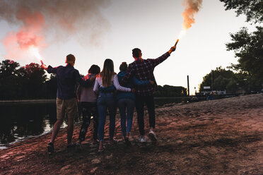 Group of friends walking at the riverside in the evening with torches - UUF14852