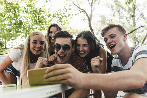 Gruppe von glücklichen Freunden, die im Freien auf ihr Handy schauen, lizenzfreies Stockfoto