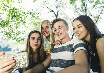 Gruppe von lächelnden Freunden, die im Freien auf ihr Handy schauen - UUF14866