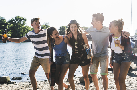 Group of happy friends walking arm in arm at the riverside stock photo