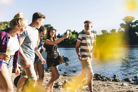 Gruppe von glücklichen Freunden beim Spaziergang am Flussufer, lizenzfreies Stockfoto