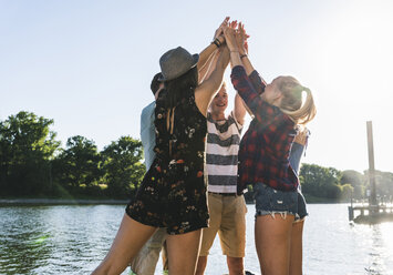 Group of friends putting their hands together at the riverside - UUF14893