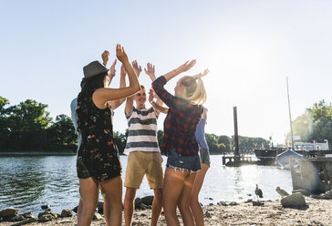 Group of friends raising their hands at the riverside - UUF14895