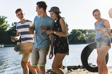 Group of happy friends with cell phones walking at the riverside - UUF14897