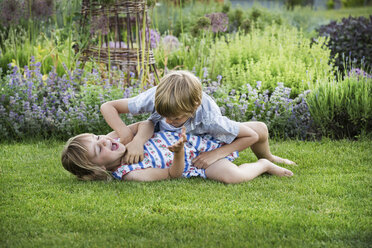 Lächelnder Junge und lächelndes Mädchen in einem Garten, sie toben, spielen zusammen, spielen auf einem Rasen. - MINF04421