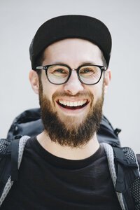 Porträt eines lachenden, schwarz gekleideten Mannes mit Rucksack - NGF00464