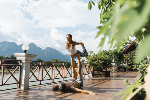 Laos, Vang Vieng, Junges Paar beim Akro-Yoga auf einer Terrasse - AFVF01217