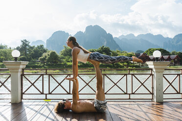Laos, Vang Vieng, Junges Paar beim Akro-Yoga auf einer Terrasse - AFVF01220