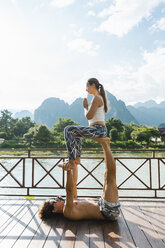 Laos, Vang Vieng, Young couple doing acro-yoga on a terrace - AFVF01222