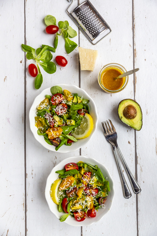 Feldsalat mit bunten Tomaten, Avocado, Parmesan und Kurkuma-Zitronen-Dressing, lizenzfreies Stockfoto