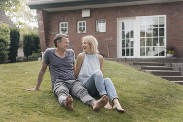 Happy mature couple sitting in garden of their home - JOSF02448