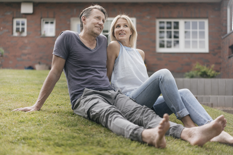 Lächelndes reifes Paar sitzt im Garten seines Hauses, lizenzfreies Stockfoto