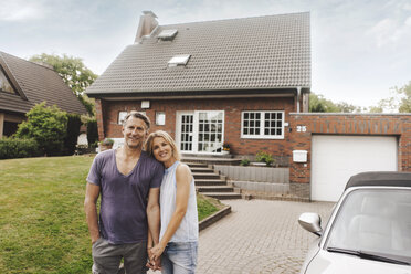 Portrait of smiling mature couple standing in front of their home - JOSF02455