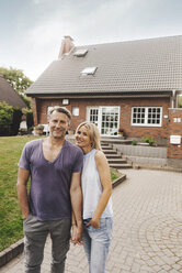 Portrait of smiling mature couple standing in front of their home - JOSF02458