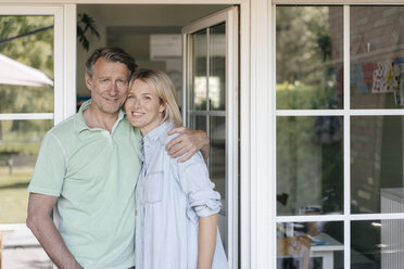 Portrait of smiling mature couple at French window - JOSF02469