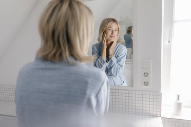 Mature woman looking in bathroom mirror - JOSF02486