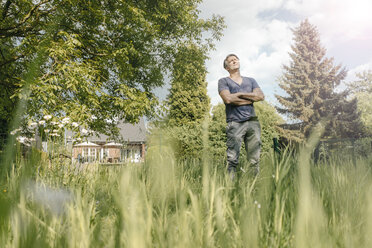 Älterer Mann steht im Garten seines Hauses - JOSF02497