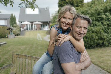 Portrait of smiling mature couple embracing in garden of their home - JOSF02502