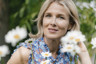 Portrait of smiling mature woman with flowers - JOSF02522