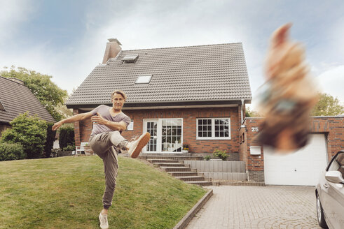 Mature man kicking away garden gnome in front of his home - JOSF02534