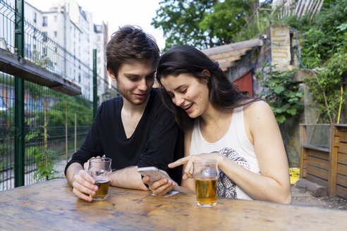 Junges Paar an einer Bar im Freien mit Bier und Mobiltelefon - AFVF01228