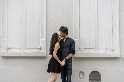 Junges verliebtes Paar, das sich vor einem Gebäude küsst - AFVF01248