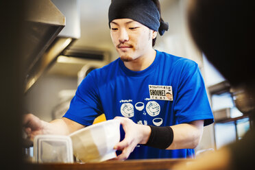 Die Küche eines Ramen-Nudelladens: Ein Koch bereitet Schüsseln mit Ramen-Nudeln in Brühe zu, einer Spezialität und einem Fastfood-Gericht. - MINF04693