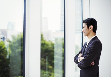 A businessman in the office, by a large window, looking out. - MINF04704