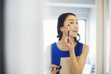 A business woman preparing for work, doing her make up. - MINF04711