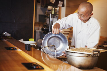 Ein Küchenchef, der in einer kleinen Großküche arbeitet, ein Itamae oder Meisterkoch, der Sushi zubereitet. - MINF04720