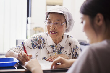 A mature woman at a desk in the office of a fast food unit and noodle production factory. - MINF04726