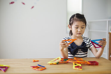 A girl sitting playing with coloured geometric shapes. - MINF04739