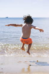 A boy in swimming trunks jumping over waves on the sea shore. - MINF04788